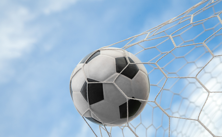 Bola de futebol na rede com fundo de céu azul