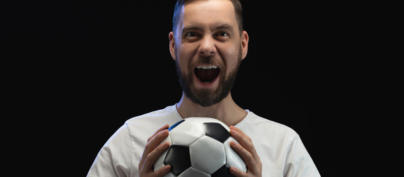 Homem gritando e com bola de futebol na mão